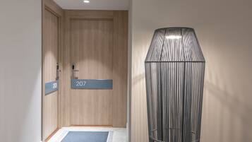 A hallway with wooden doors labeled 208 and 207, and a metallic, ribbed structure on the right.