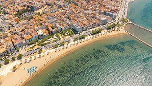 Vista aèria d'una ciutat costanera amb edificis urbans densos, una platja i un moll.