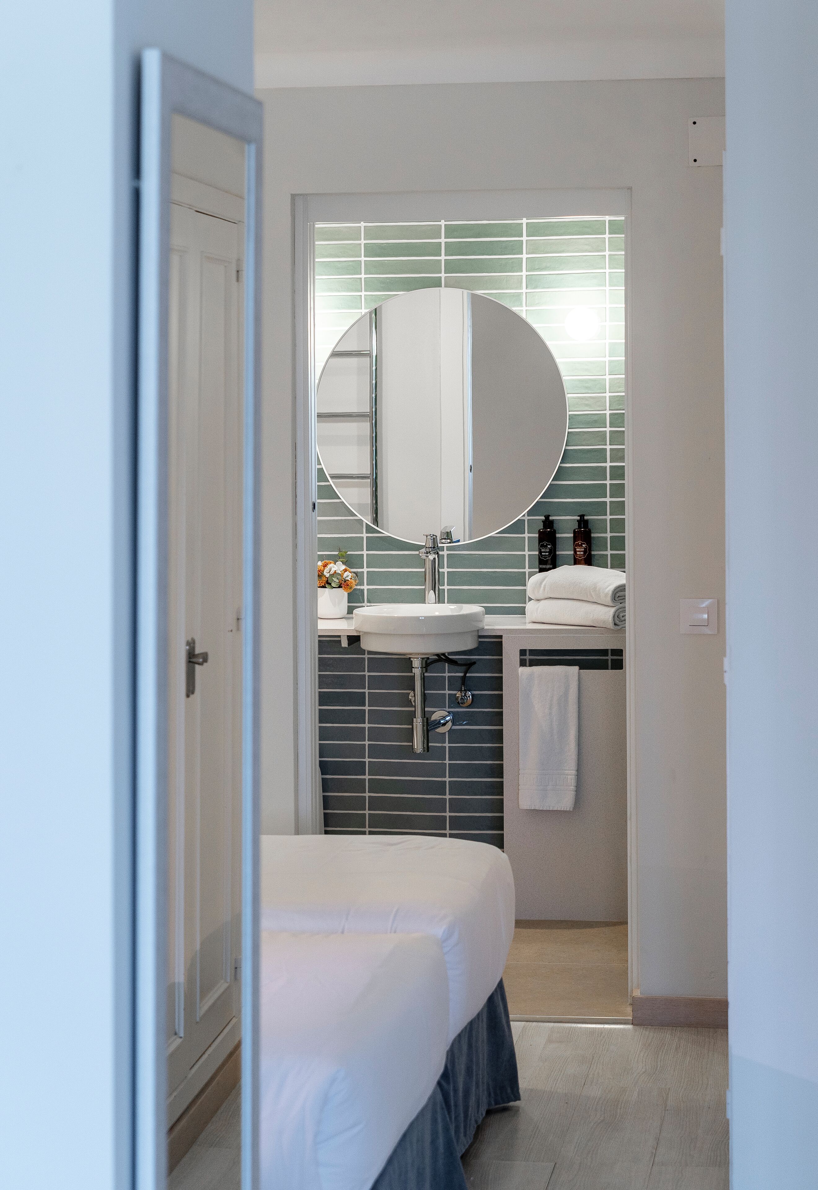 Een moderne badkamer met een witte wastafel, een grote spiegel en een handdoek aan de muur.