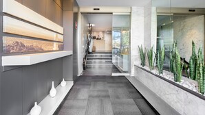 Un rebedor d'hotel modern amb una recepció, una escala i una exhibició de plantes.