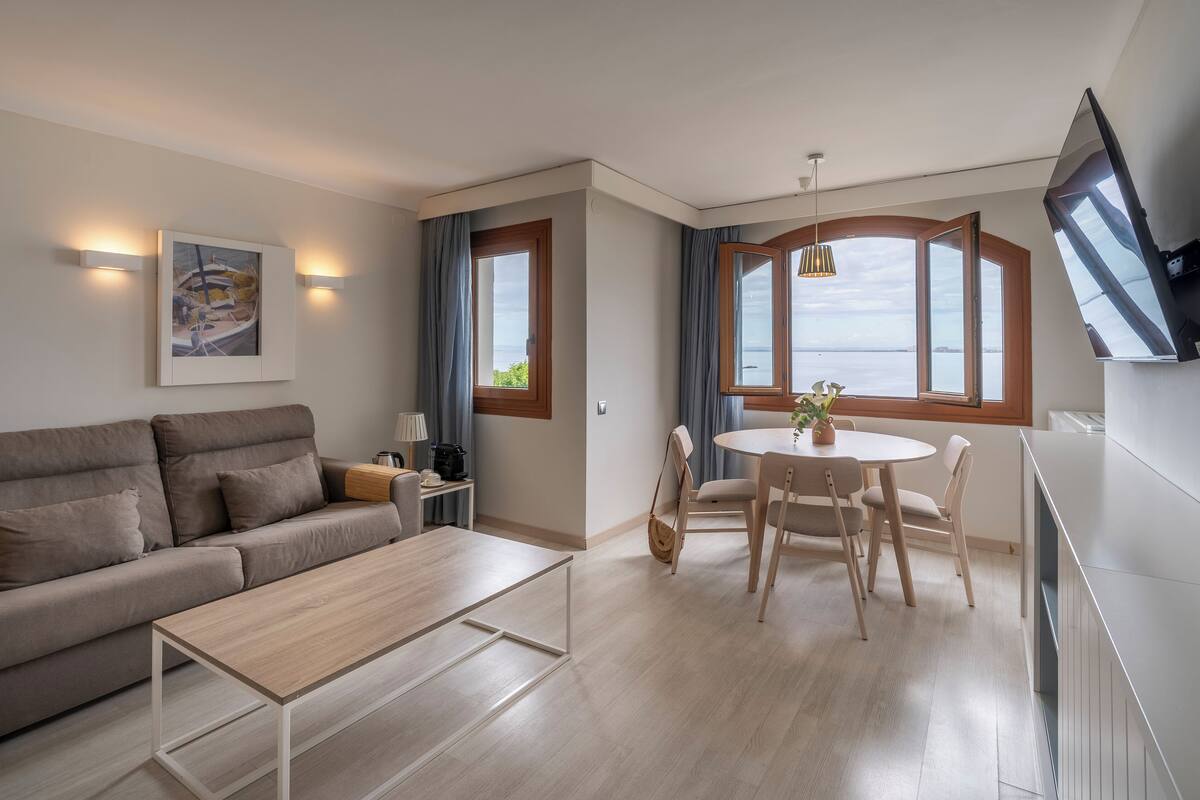 Un salon moderne avec un canapé, une table basse, une table à manger et un tableau accroché au mur.