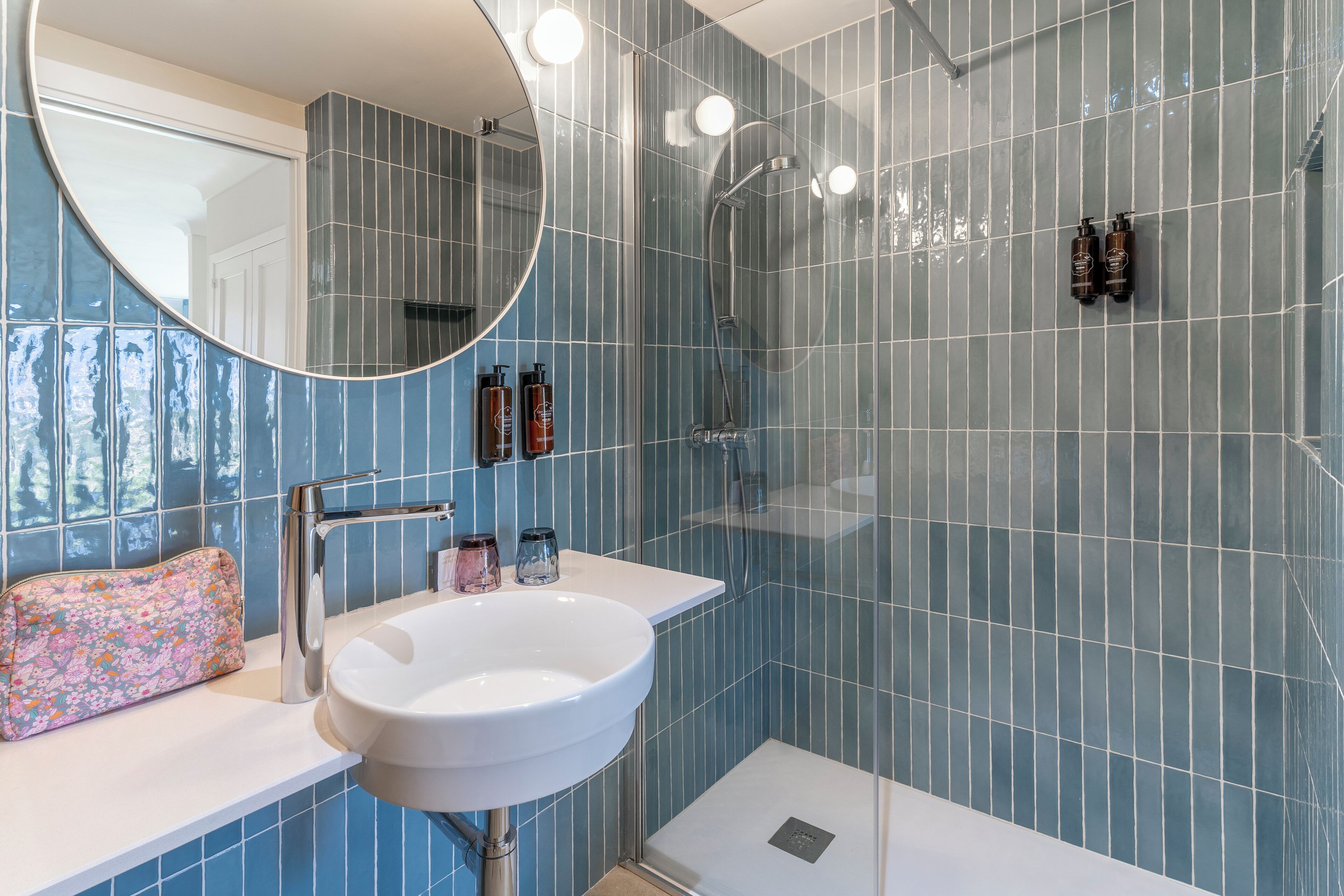 A bathroom with a white sink, a mirror, and a shower area.