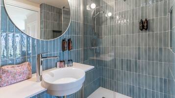 A bathroom with a white sink, a mirror, and a shower area.
