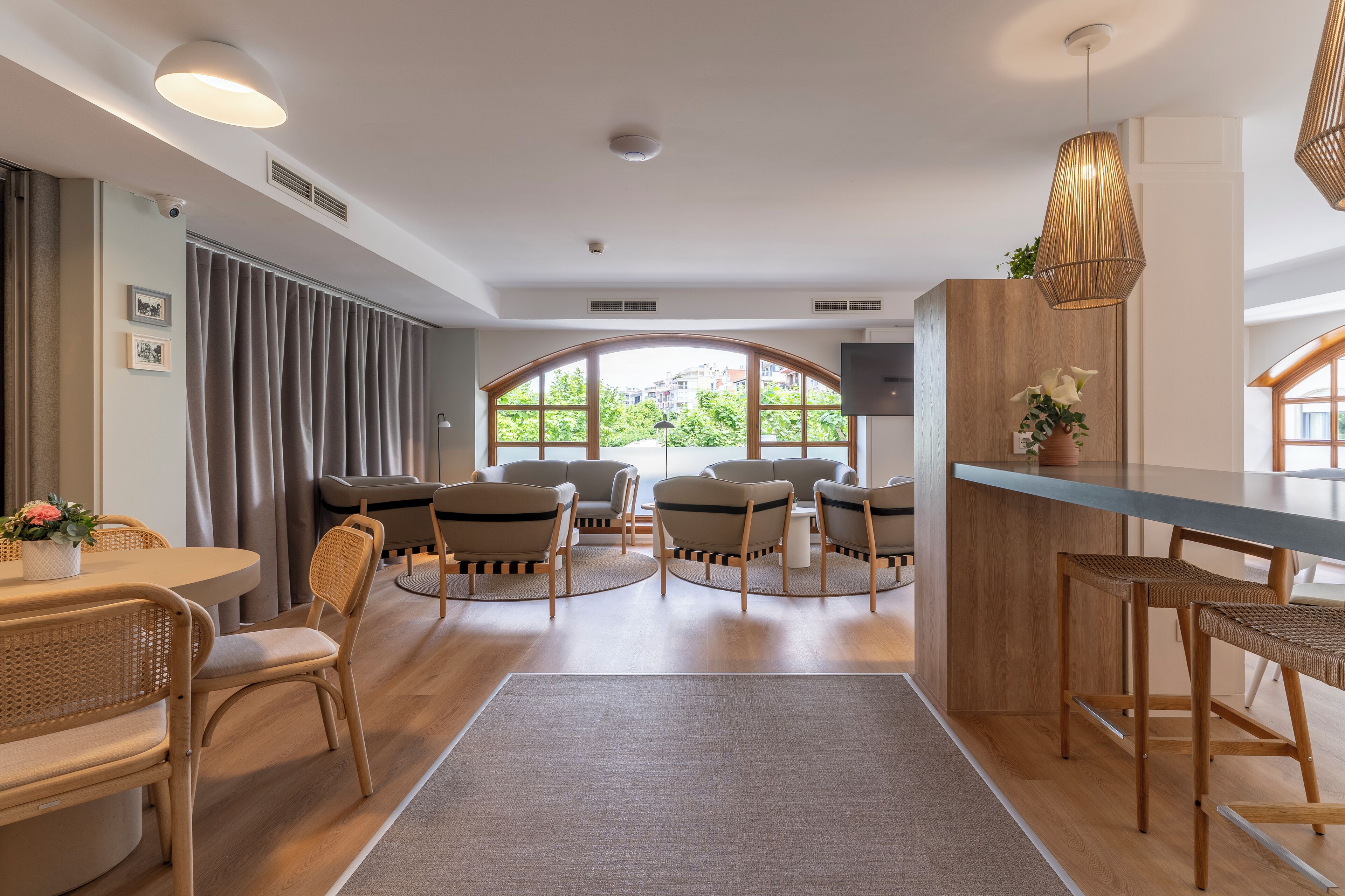 Habitación de hotel moderna con zona de comedor, asientos y vistas a través de amplios ventanales.