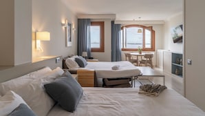 Habitació d'hotel amb dos llits, una taula de dinar i vista al mar.
