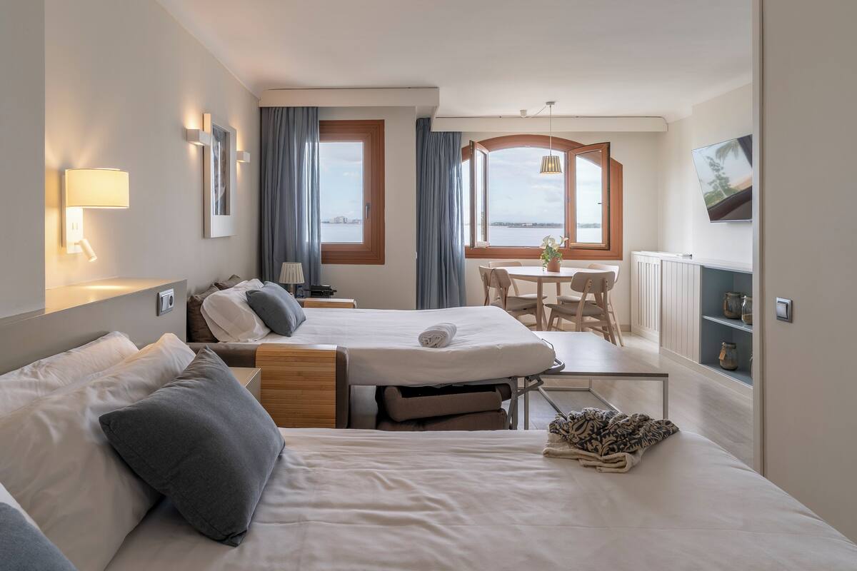 Une chambre d’hôtel avec deux lits, une table à manger et vue sur la mer.