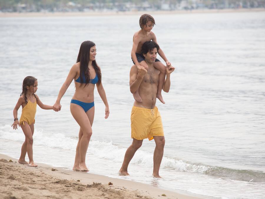 Escena de playa con gente caminando por la orilla.