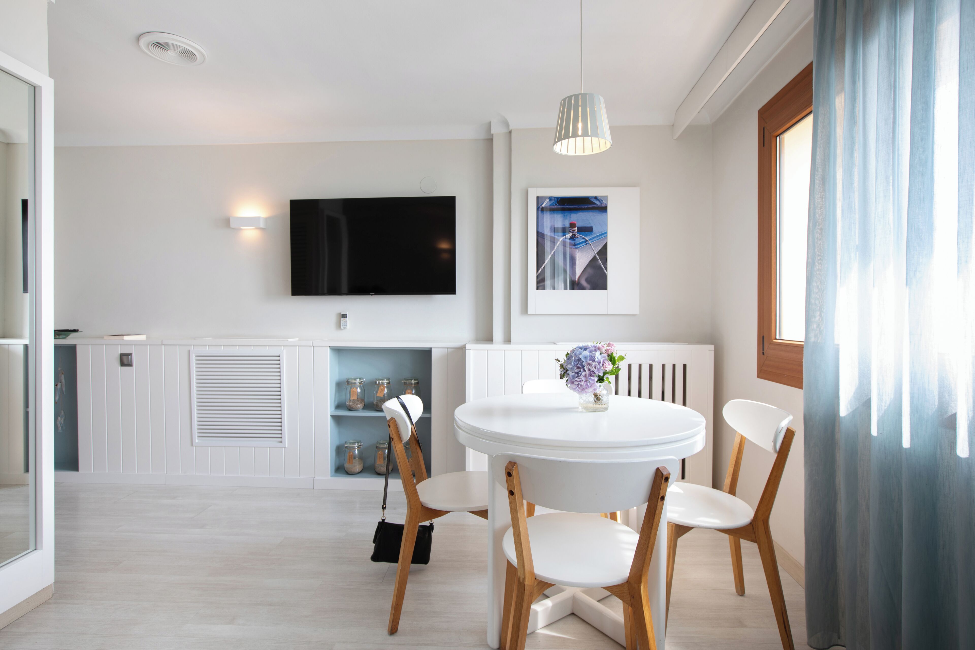 A modern kitchen with white cabinetry, a built-in oven, and a large window.
