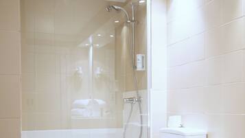 Un baño moderno con ducha envuelta en vidrio, inodoro y bidé.
