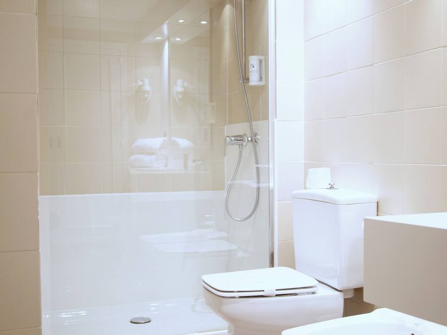 Un baño moderno con ducha envuelta en vidrio, inodoro y bidé.