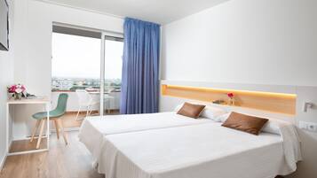 A hotel room with two beds, a desk, and a chair.