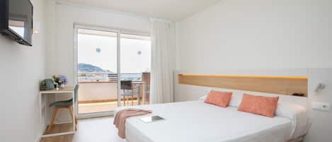A hotel room with a bed, a desk, a chair, and a TV.