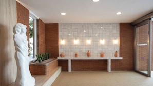 A modern interior with a white statue, a tiled wall, and a bench with decorative pots. - Hotel Prestige Sant Marc (Roses)
