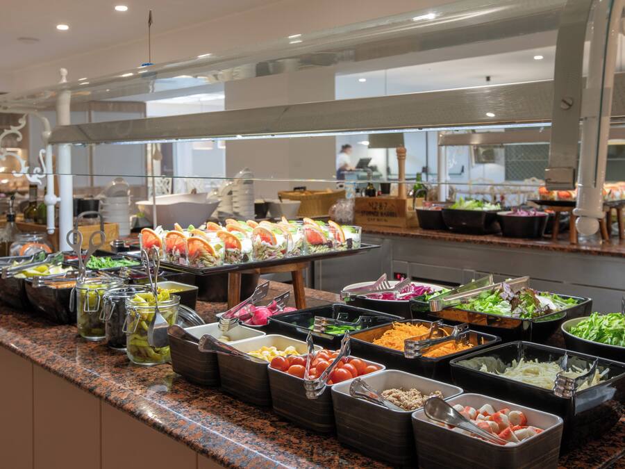 Un bufé con diversas opciones de comida, como ensaladas, frutas y verduras.