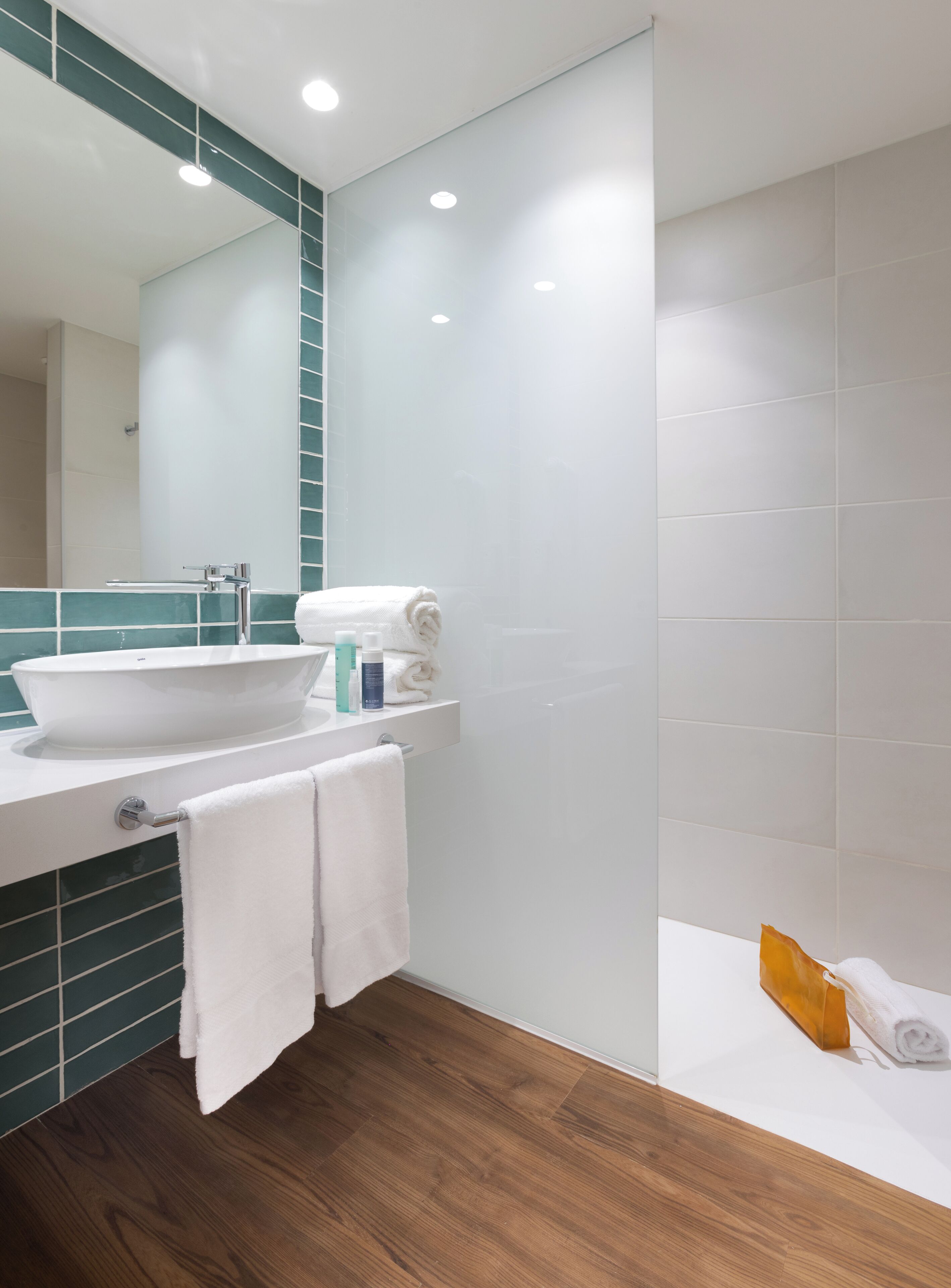A modern bathroom with a large mirror, a white sink, and a bathtub.