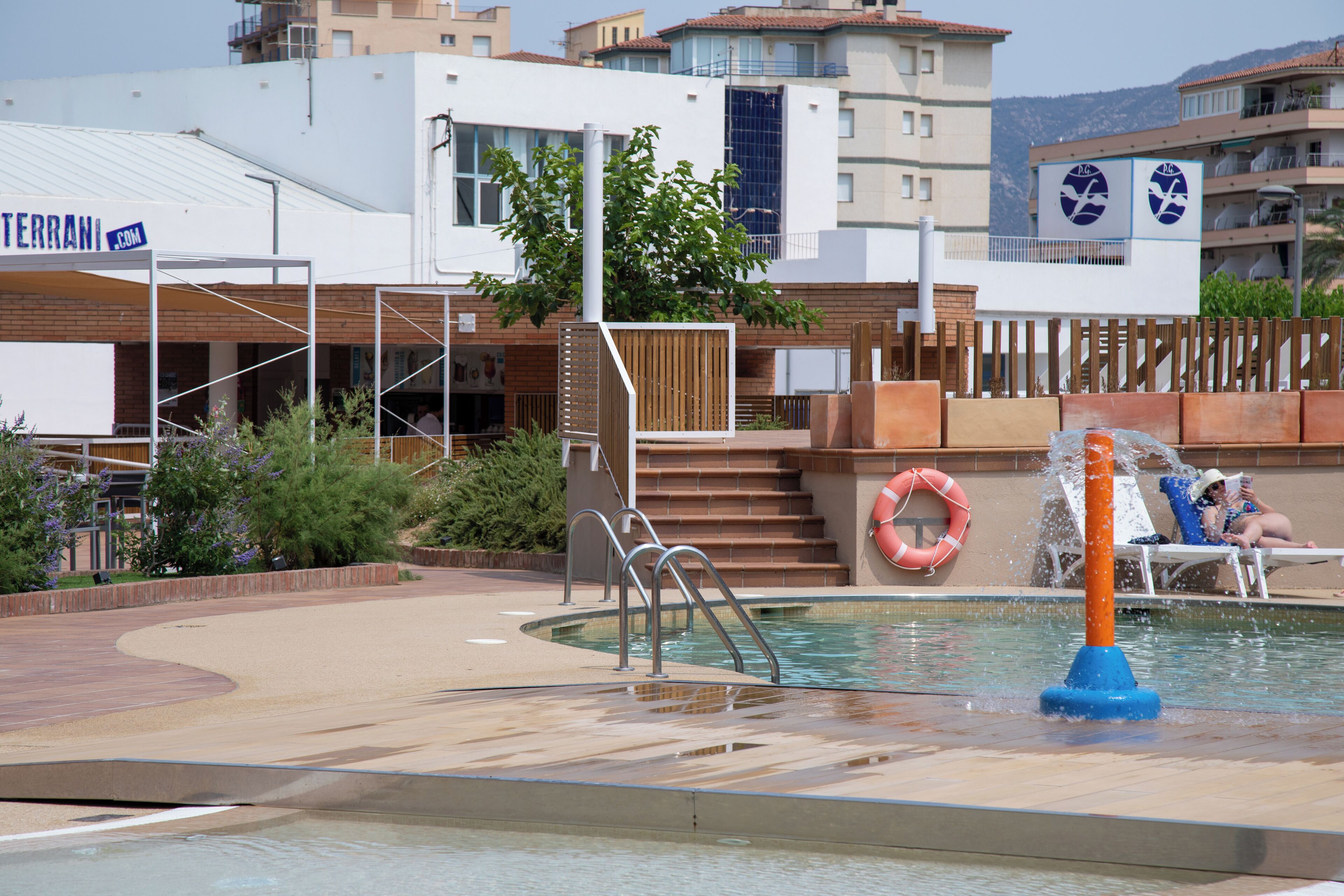 A pool area with a water feature, a lifebuoy, and a sign for 'TERRANI'.