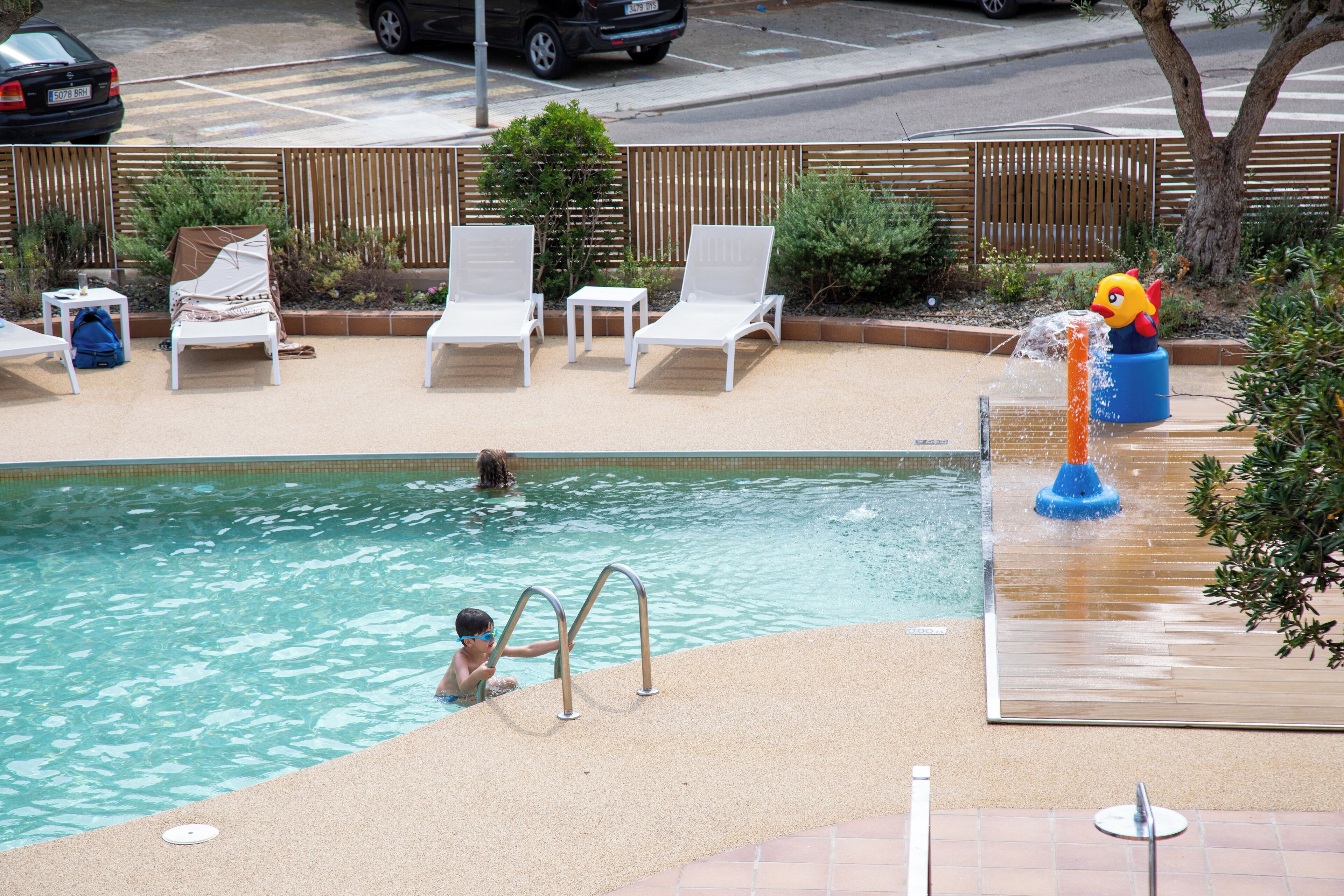 A swimming pool with lounge chairs and a water feature.