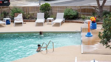 A swimming pool with lounge chairs and a water feature.