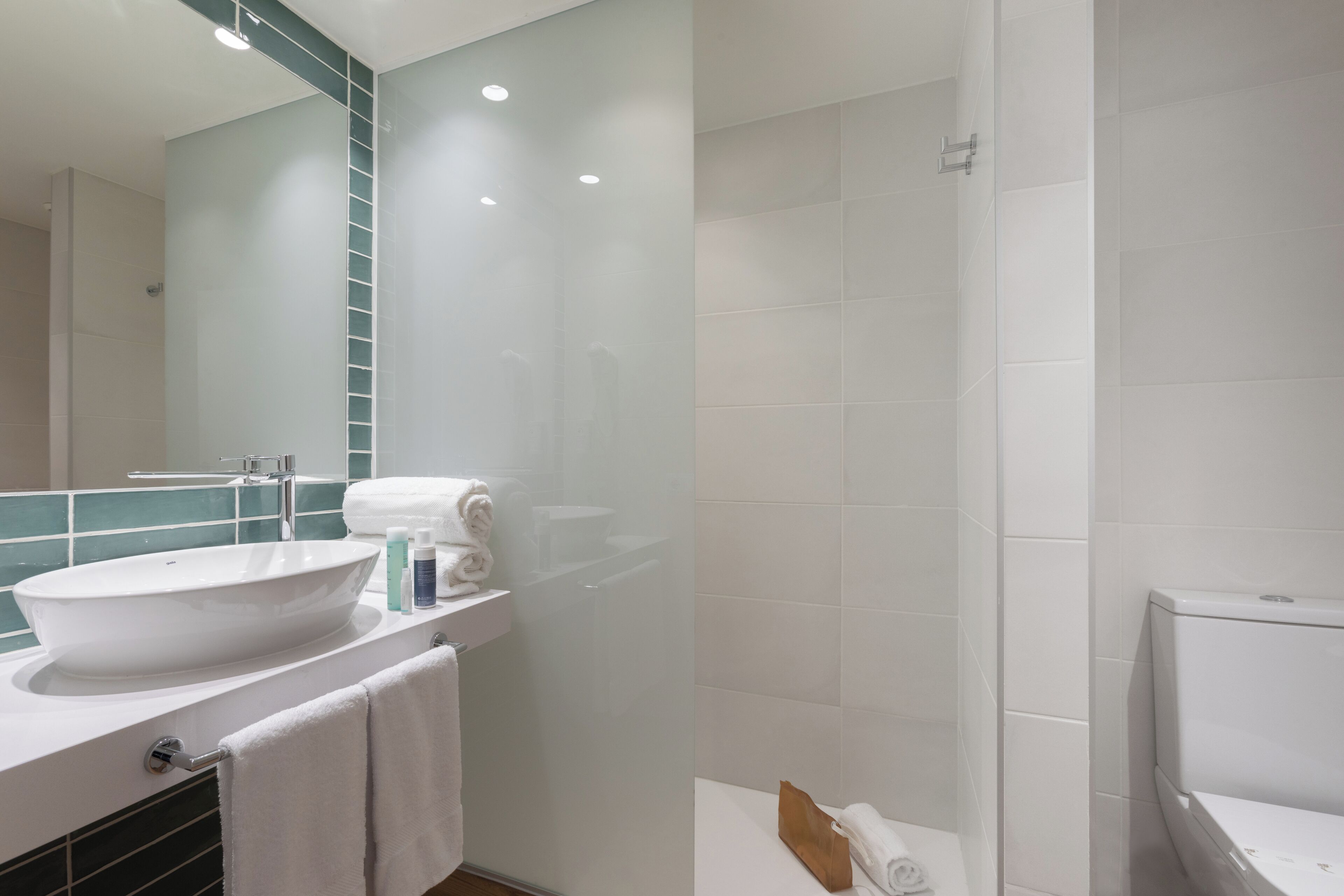 Ein modernes Badezimmer mit einem großen, weißen Waschbecken, einem Spiegel und einer Duschkabine.