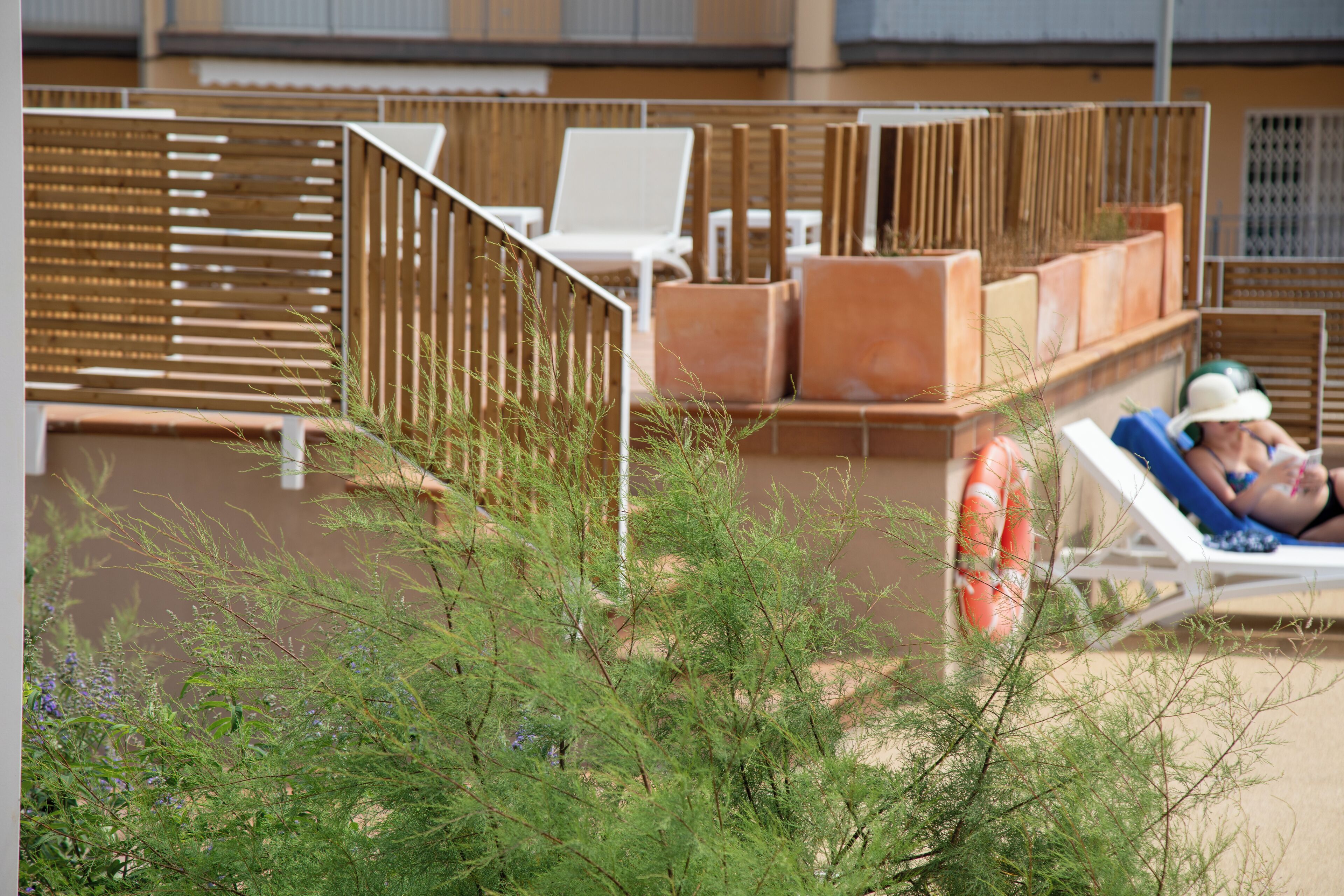 Zona junto a la piscina con sillones de descanso y una valla de madera.