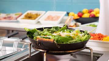 Un buffet proposant une variété de plats, notamment une salade présentée dans un plat et d’autres aliments disposés à l’arrière-plan.