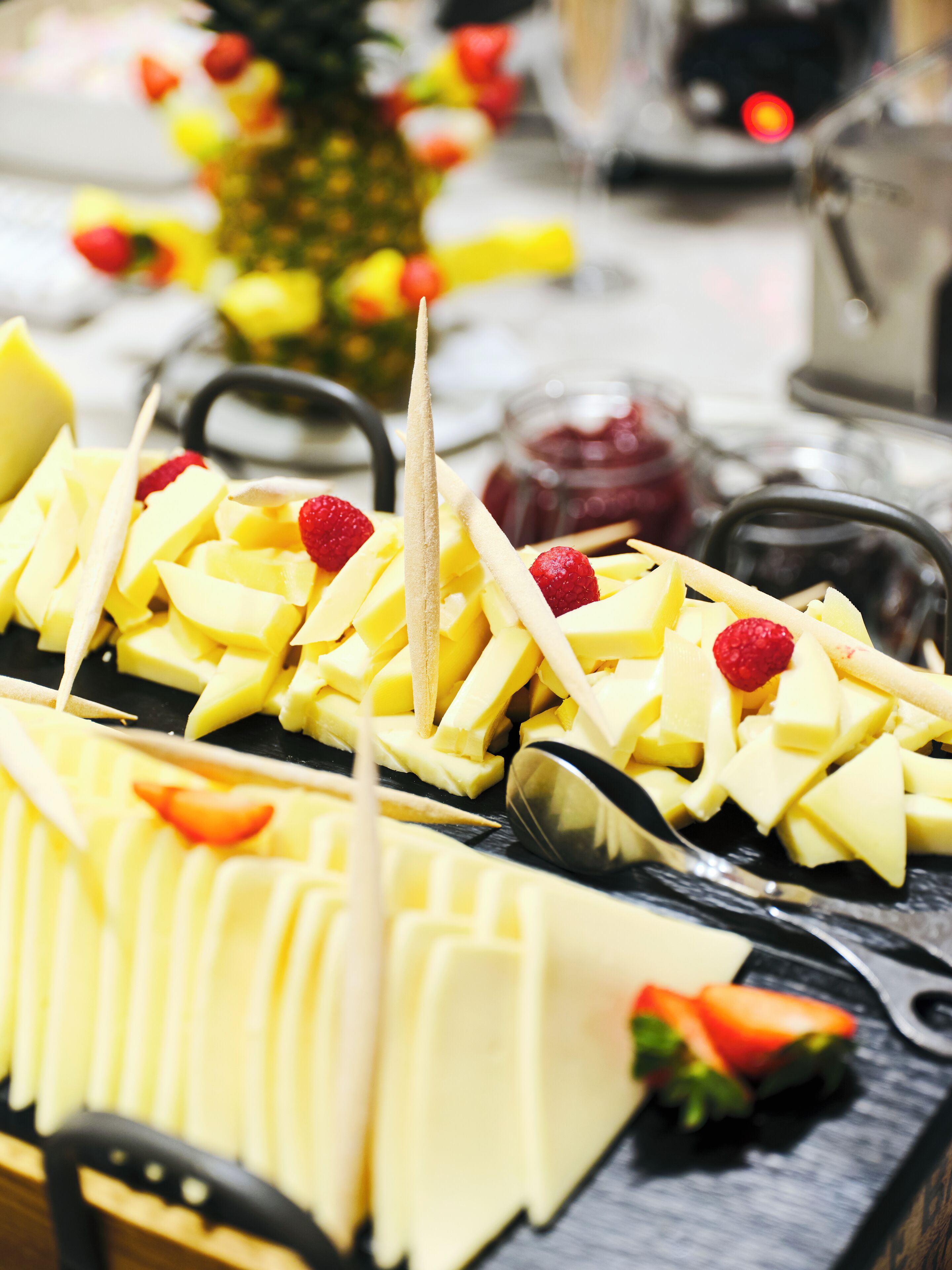 A fruit platter with sliced fruits and strawberries, arranged on a black surface.