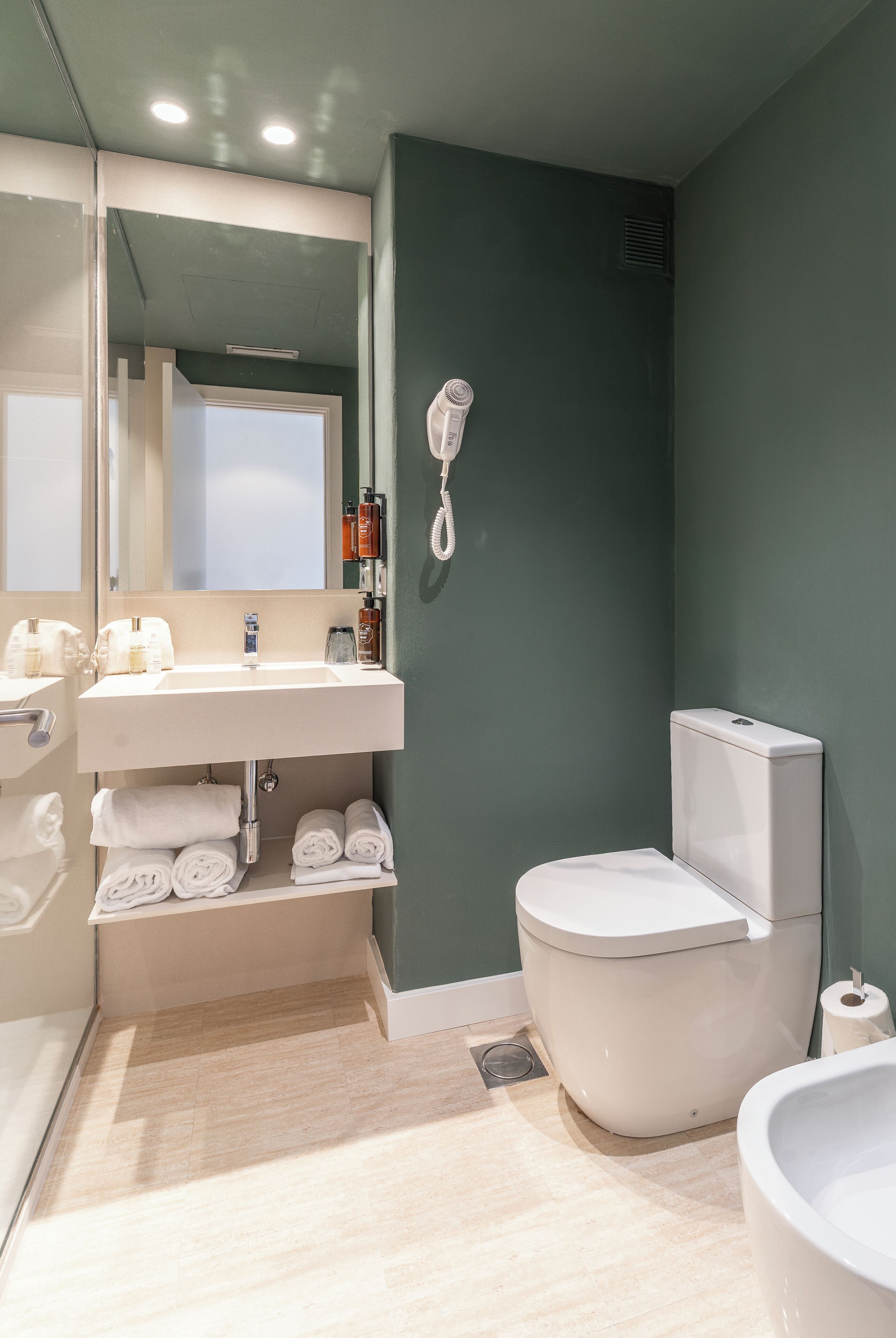 A modern bathroom with a white sink, mirror, and toilet, and a white bathtub.