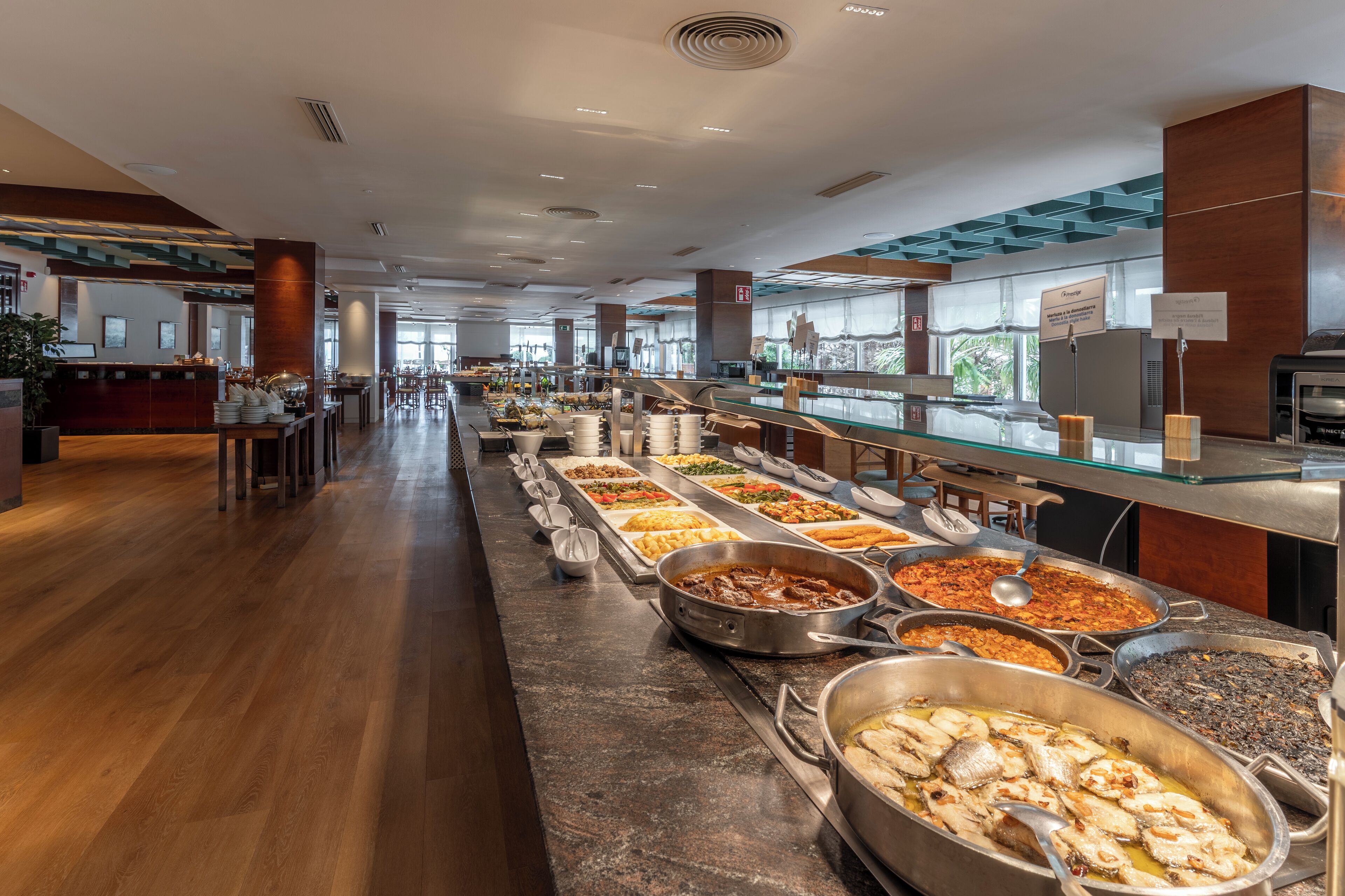 Un bufé con diversos platos, una zona de recepción y vistas al exterior.