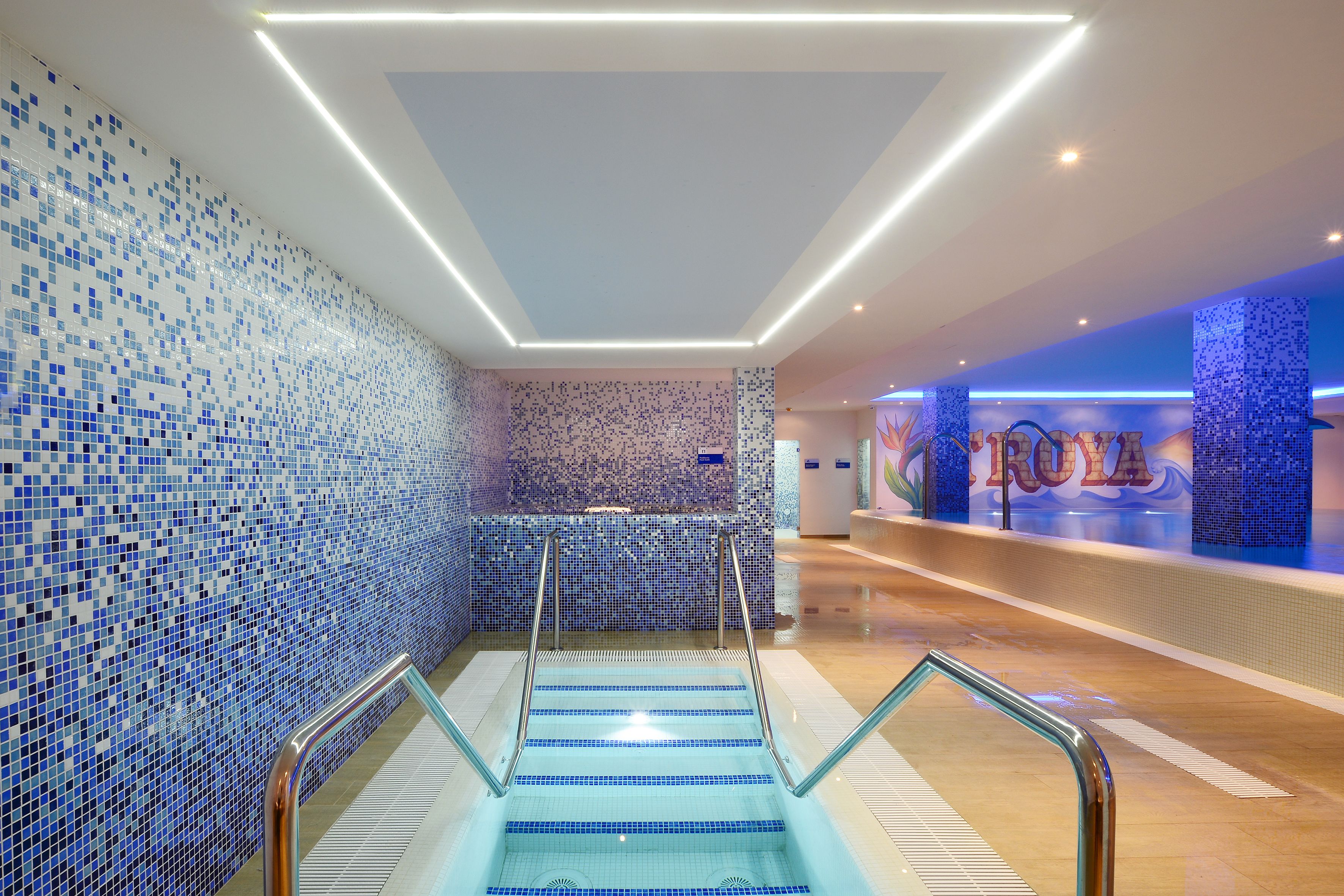 Un moderno vestíbulo de hotel con pared de azulejos, una recepción y una escalera.