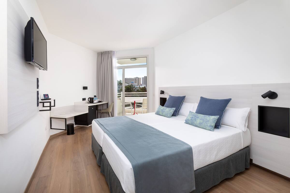 Une chambre d’hôtel moderne avec un grand lit, un bureau et une télévision.