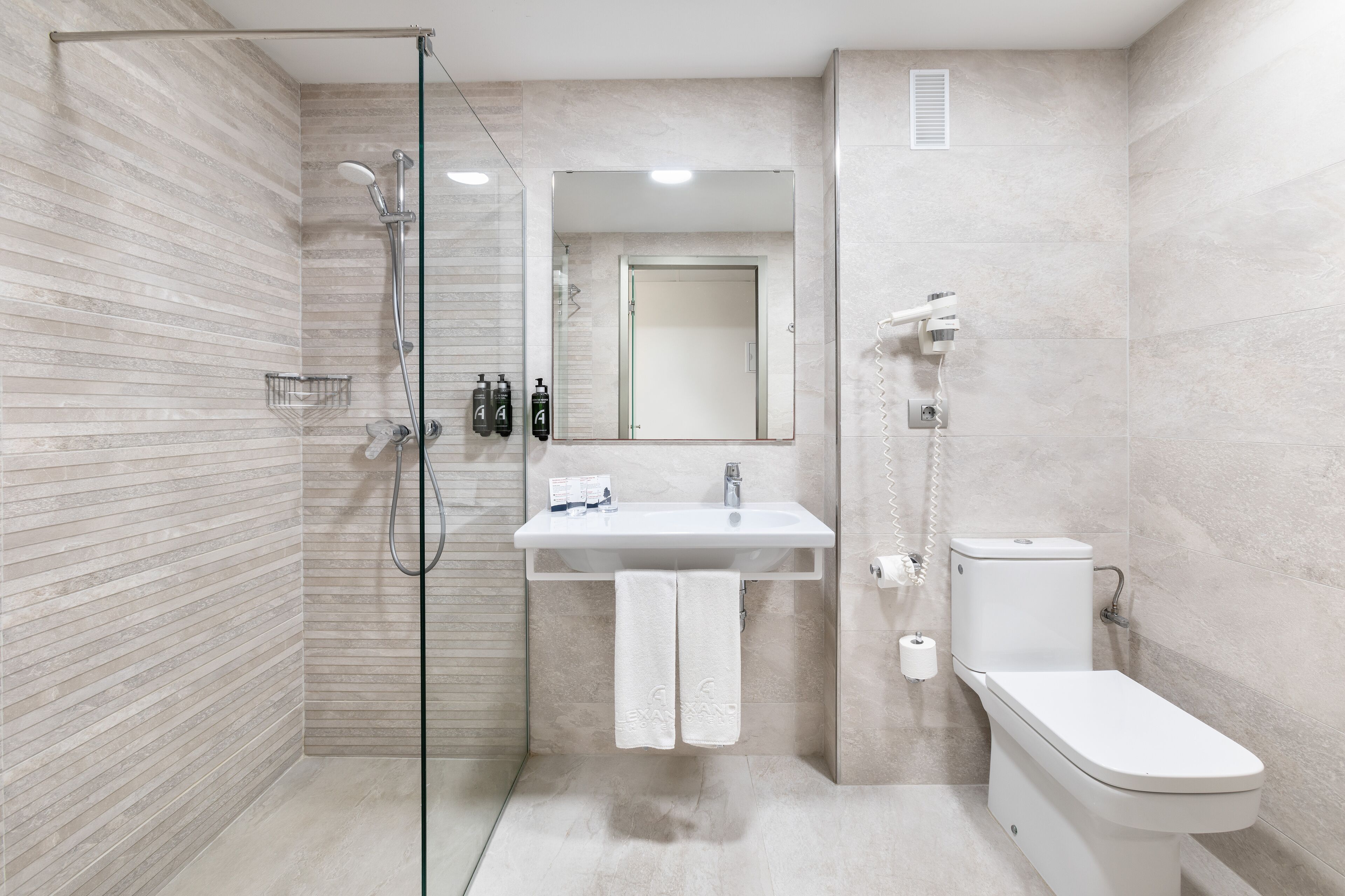 A modern bathroom with a glass-enclosed shower, a white sink, and a toilet.