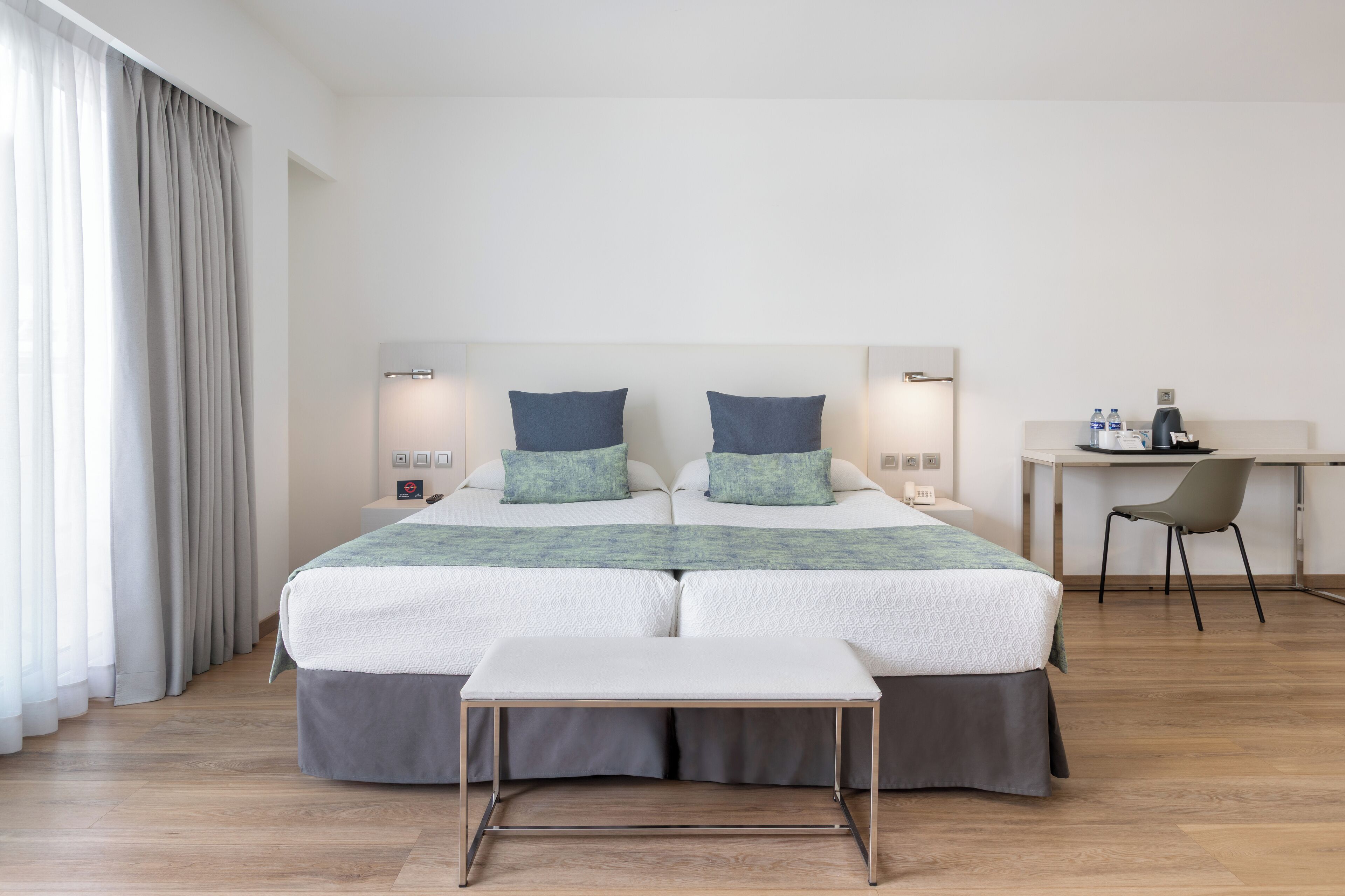 Una habitación de hotel con una cama doble, un escritorio pequeño, una silla y una mesita de noche.