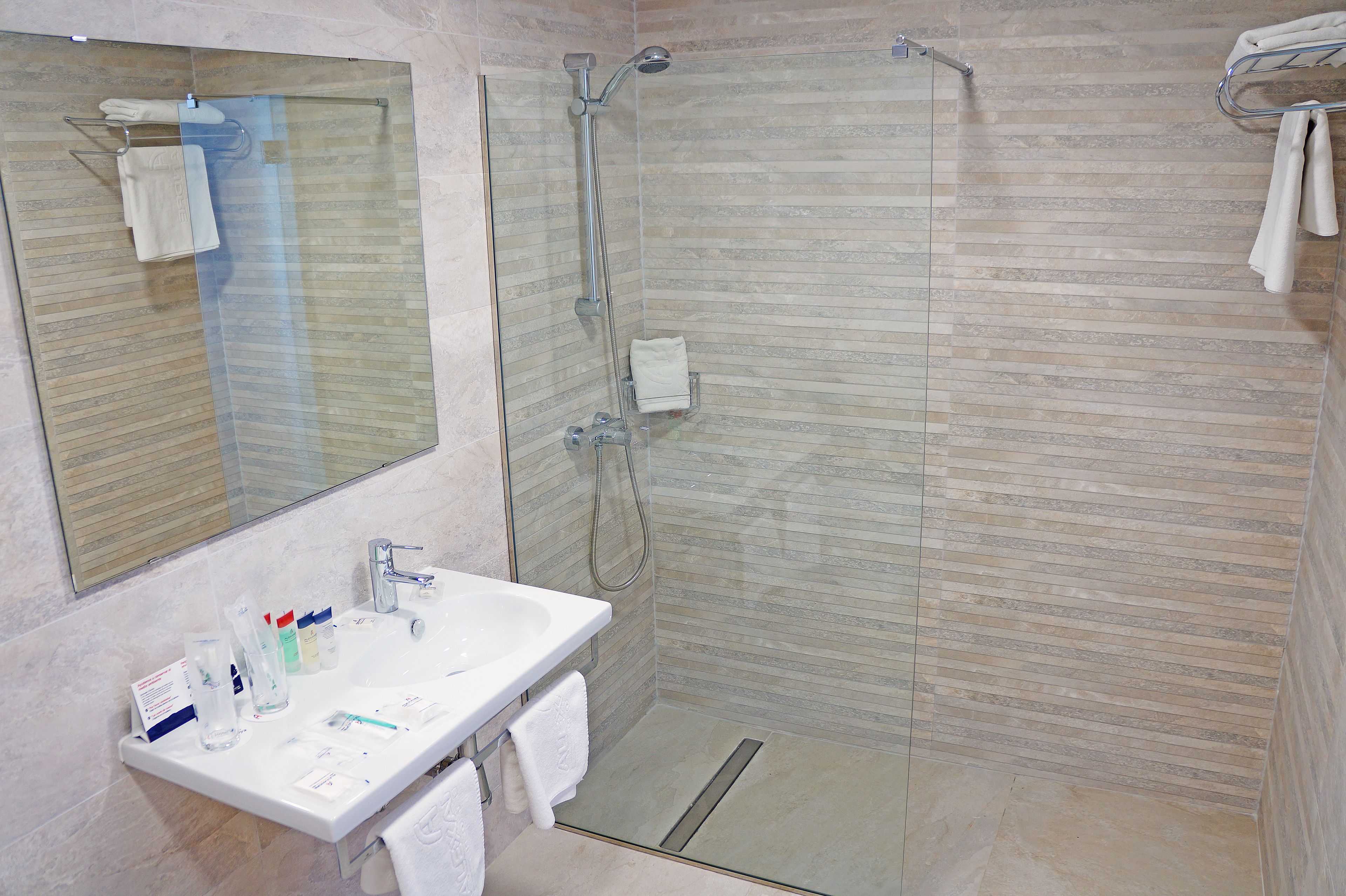 A modern bathroom with a glass-enclosed shower, a white sink, and a mirror.