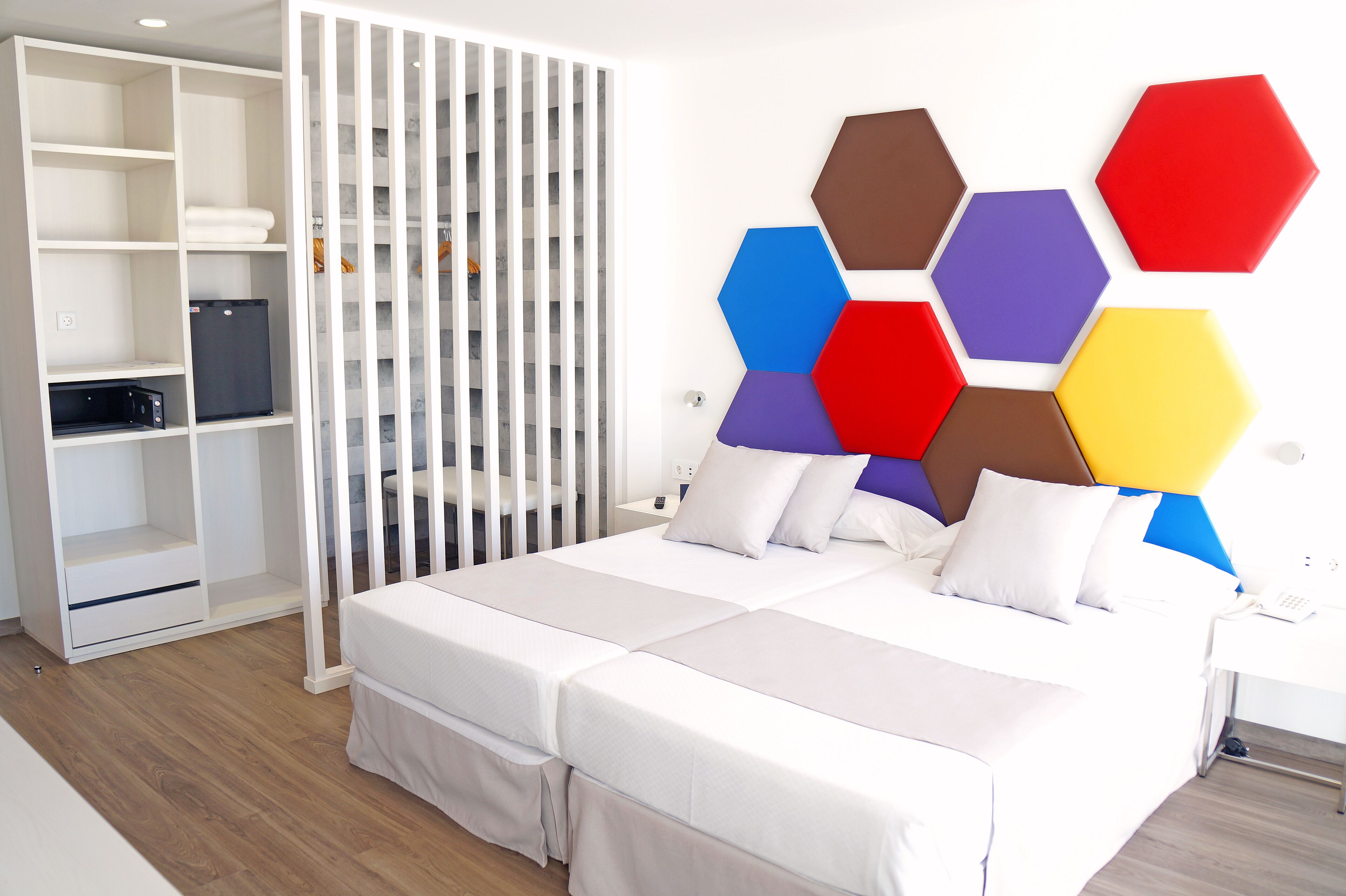 Ein modernes Schlafzimmer mit einem Bett, weißen Vorhängen und einem weißen Kleiderschrank.