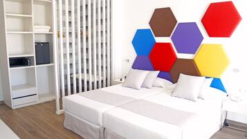 Ein modernes Schlafzimmer mit einem Bett, weißen Vorhängen und einem weißen Kleiderschrank.