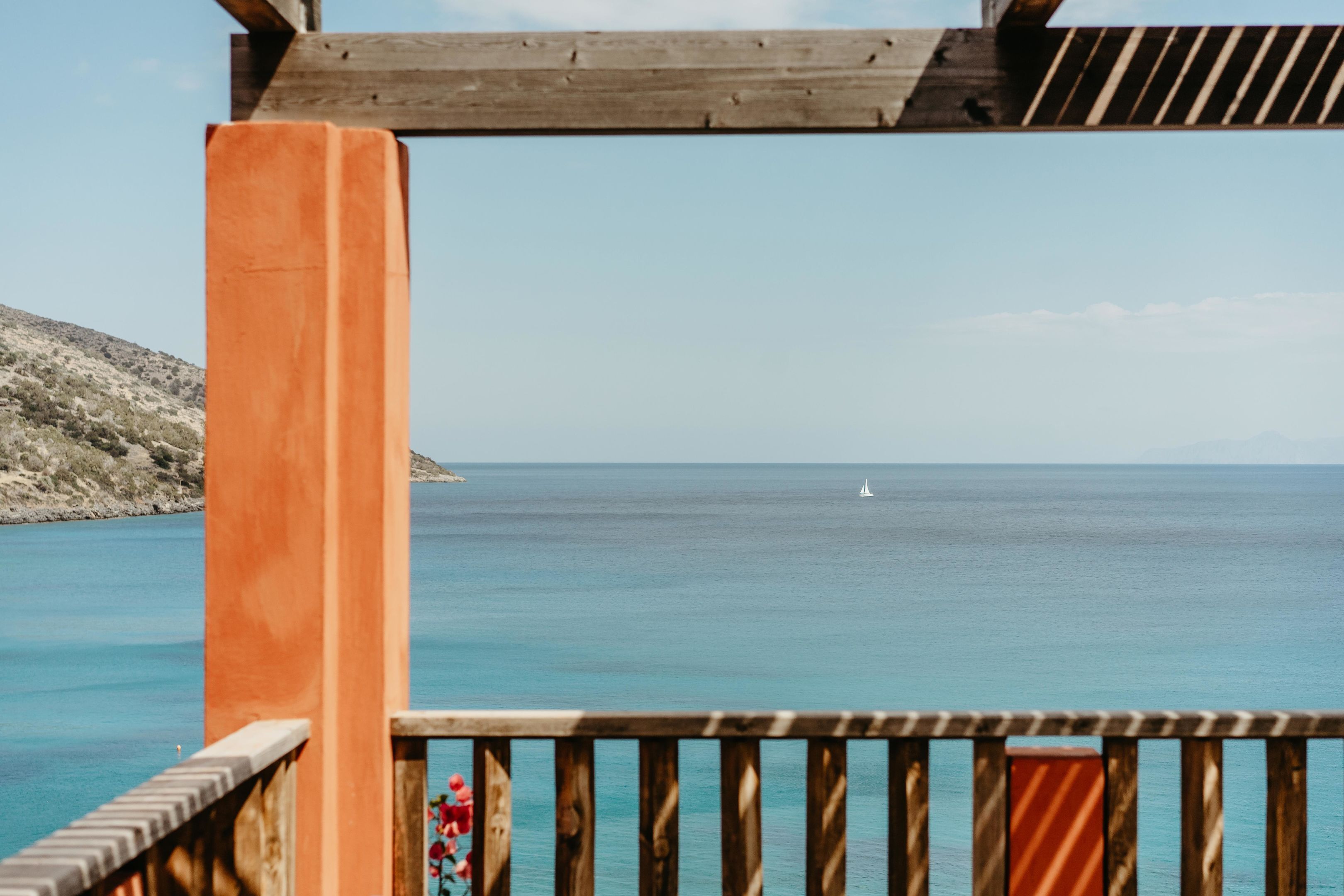 Un pontile di legno con vista sul mare e una vela all'orizzonte.