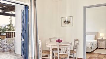 Una habitación con una mesa de comedor, sillas, una cama y una pequeña mesita de noche con una lámpara.