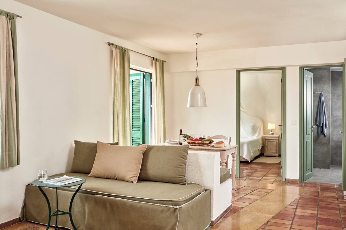 A cozy room with a sofa, a small table, a lamp, and a bed.