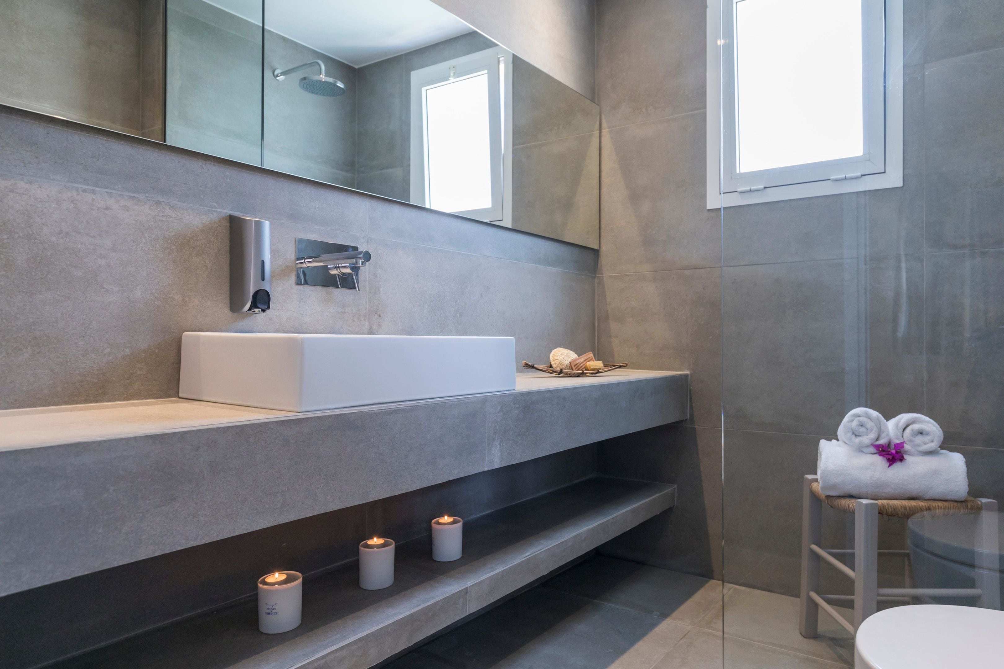 A modern bathroom with a large mirror, a white sink, and a towel rack.