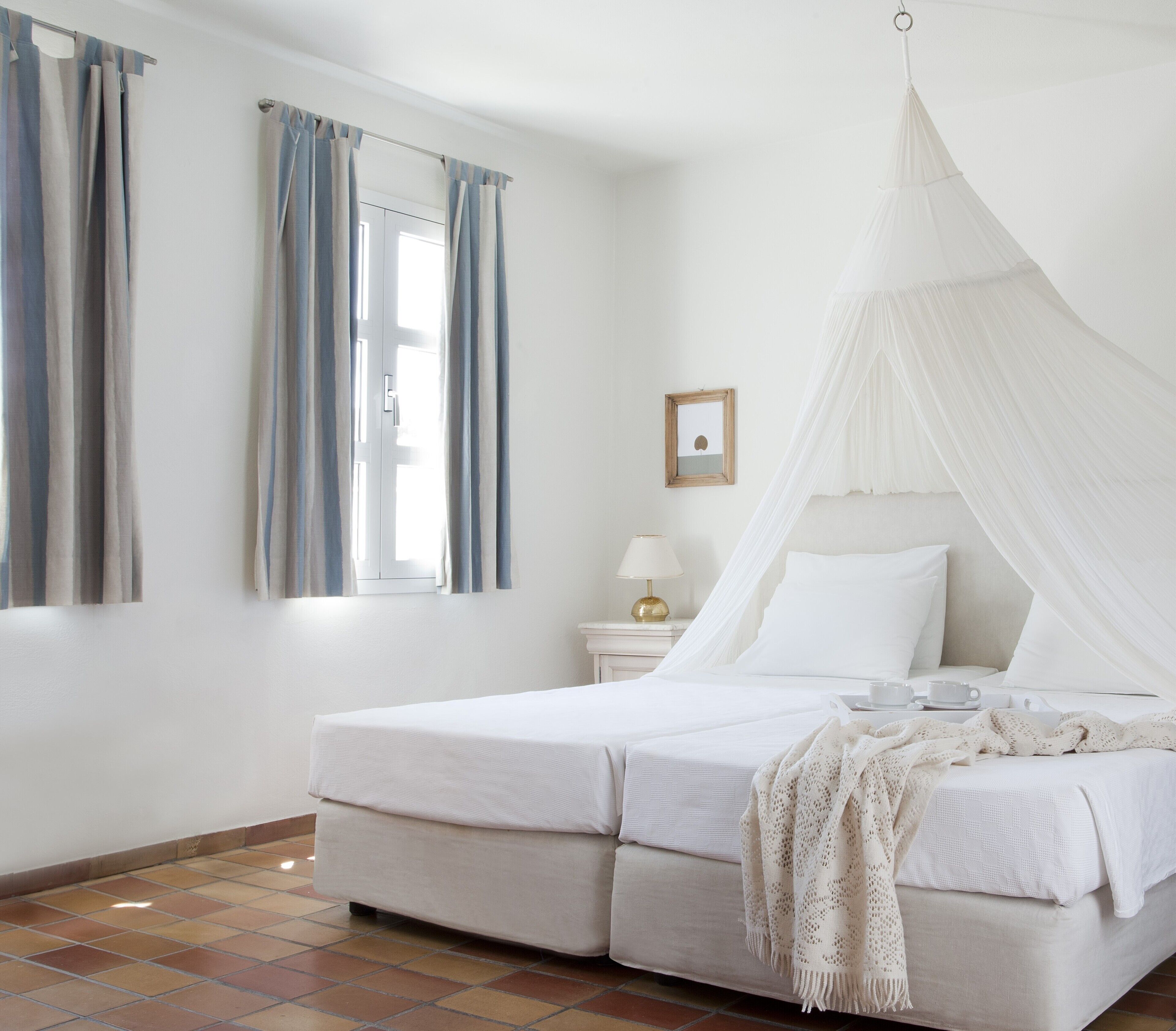 Una camera da letto con un letto, tende, un comodino, una lampada e un baldacchino.