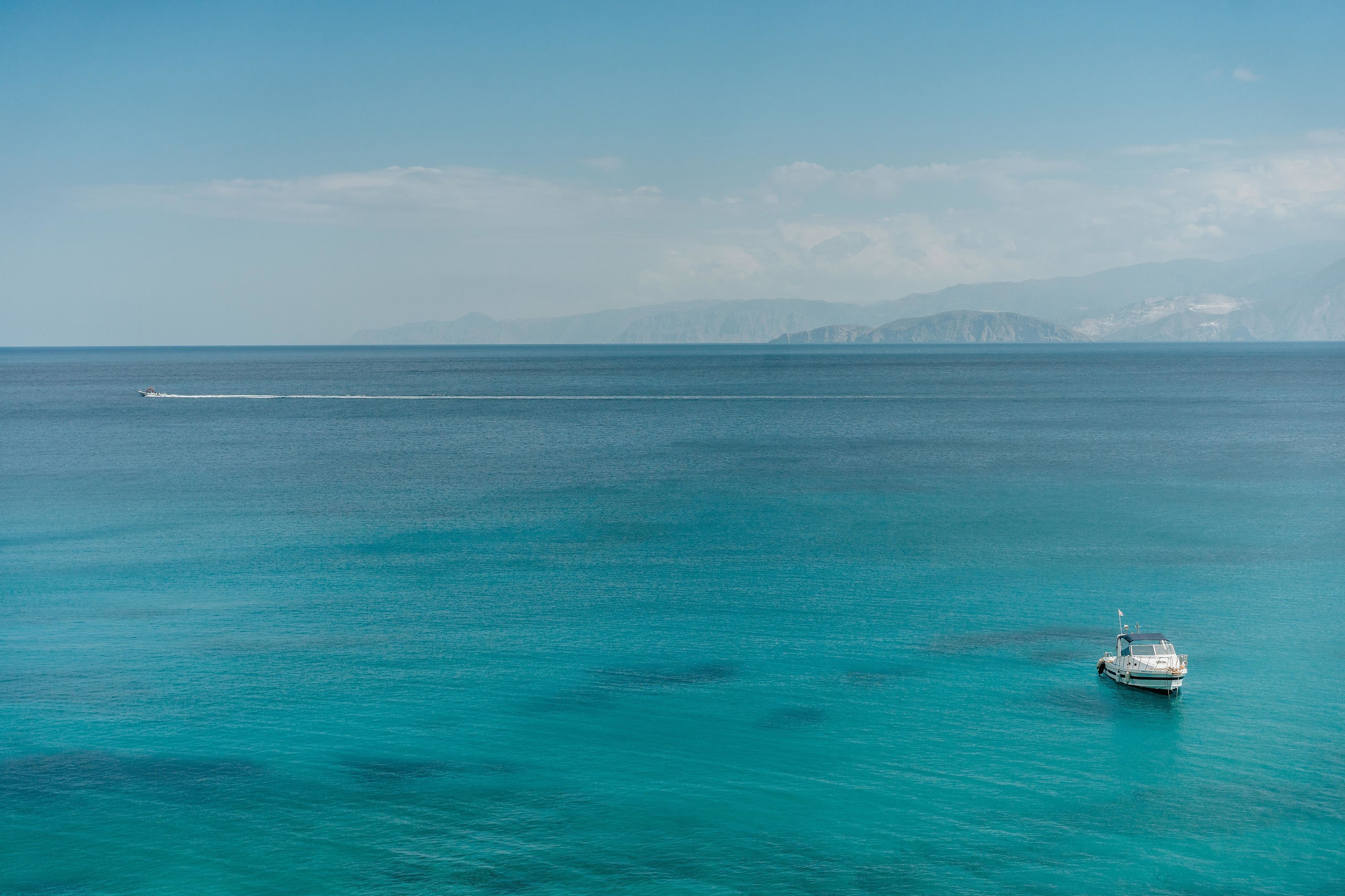 A boat in calm turquoise waters with distant mountains.