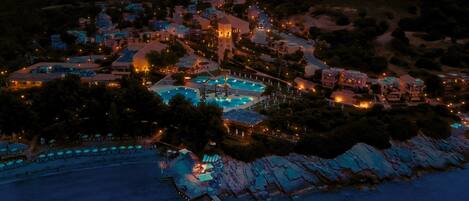 An aerial view of a coastal resort with multiple buildings, a swimming pool, and a dock.