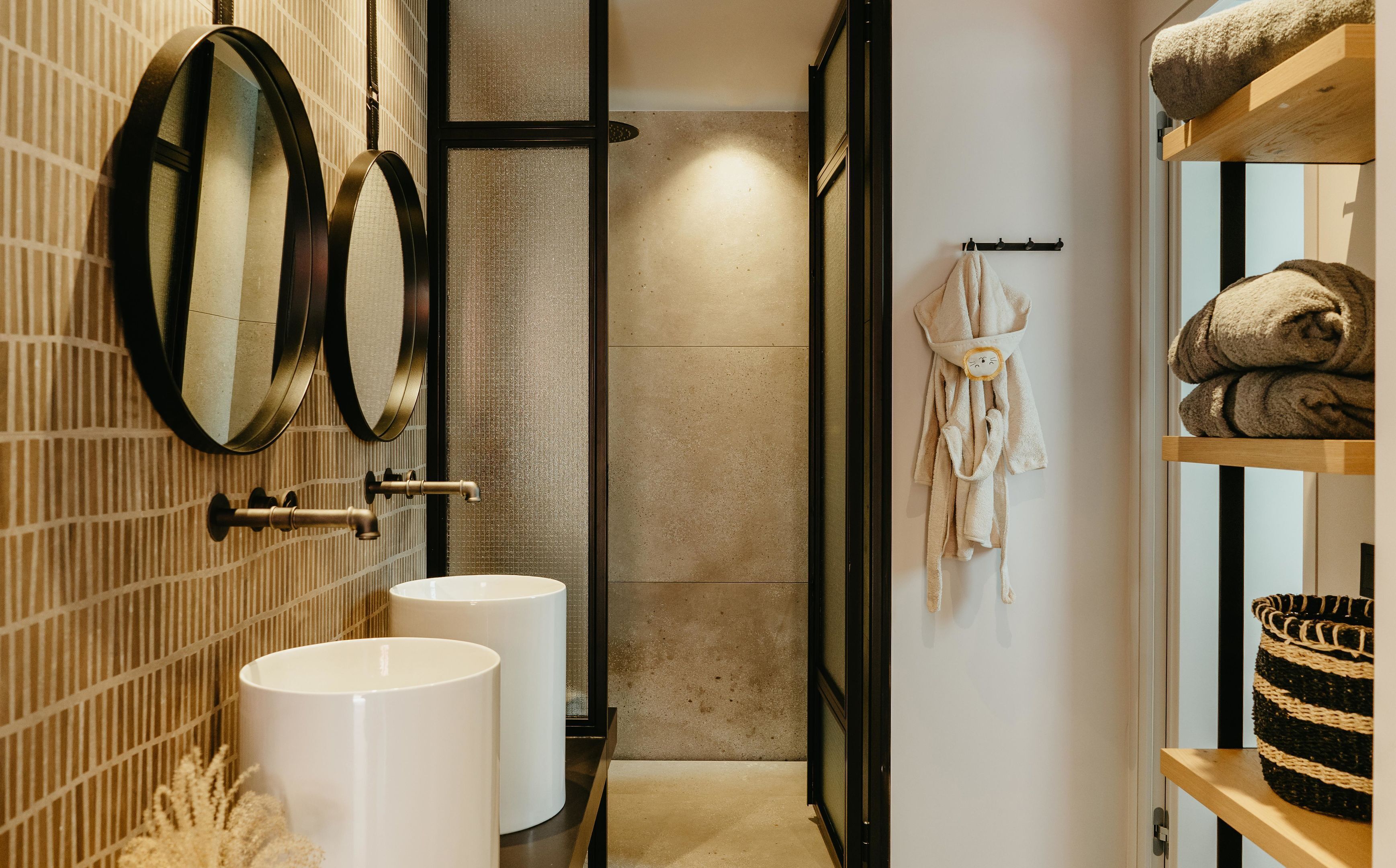 Une salle de bain moderne avec deux lavabos, un miroir et un porte-serviettes.