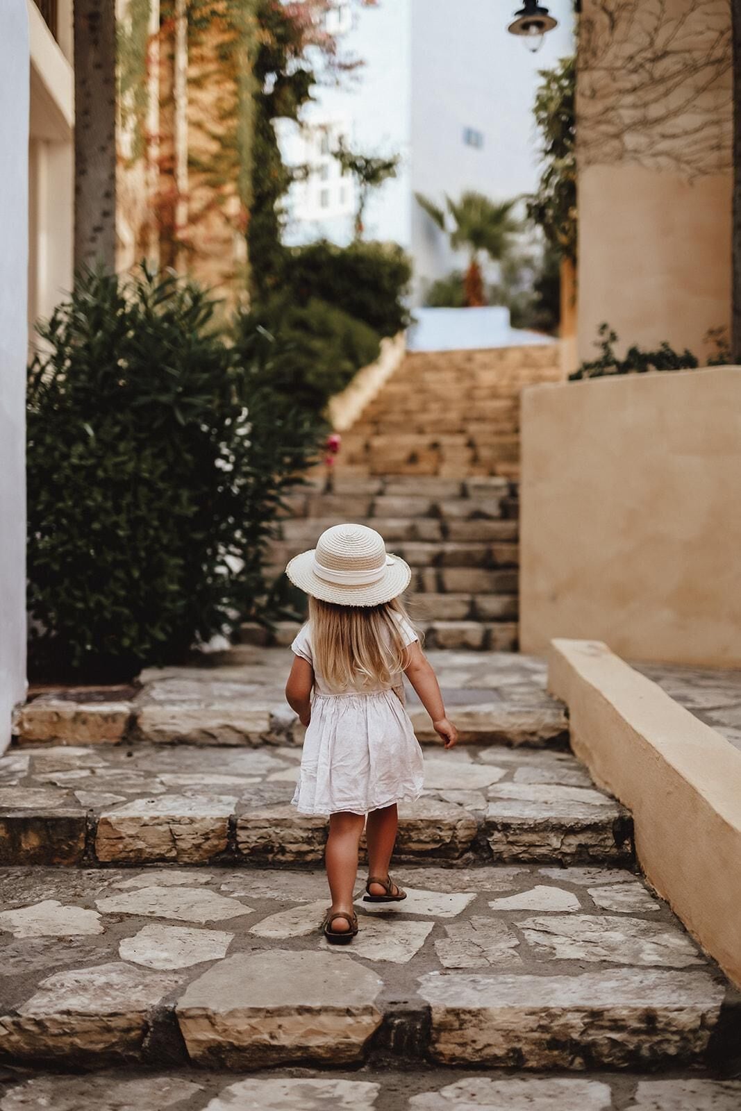 A child walking down a stone staircase in a narrow alleyway with buildings on either side.