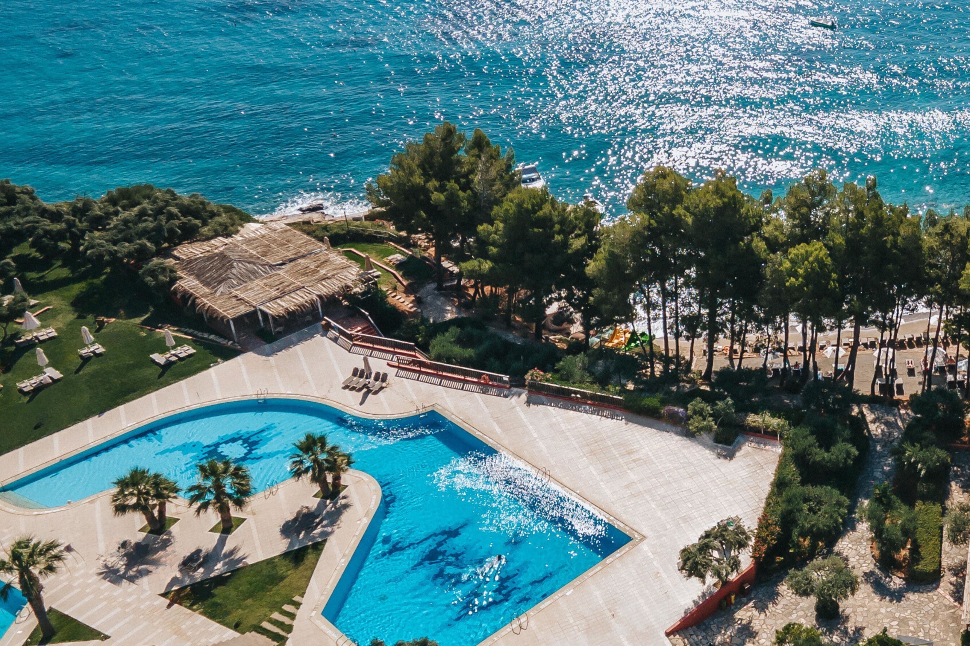 Luchtbeeld van een resort met een zwembad, terrasjes en een strand.