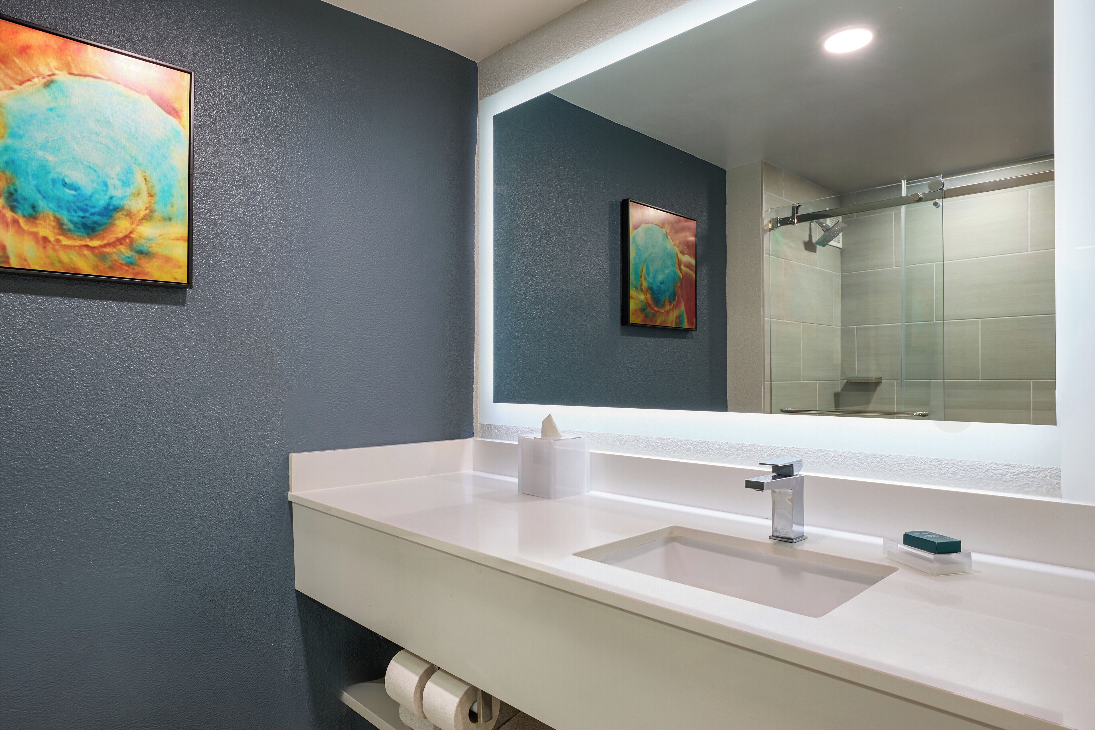 A bathroom with a white sink, a mirror, and a shower.