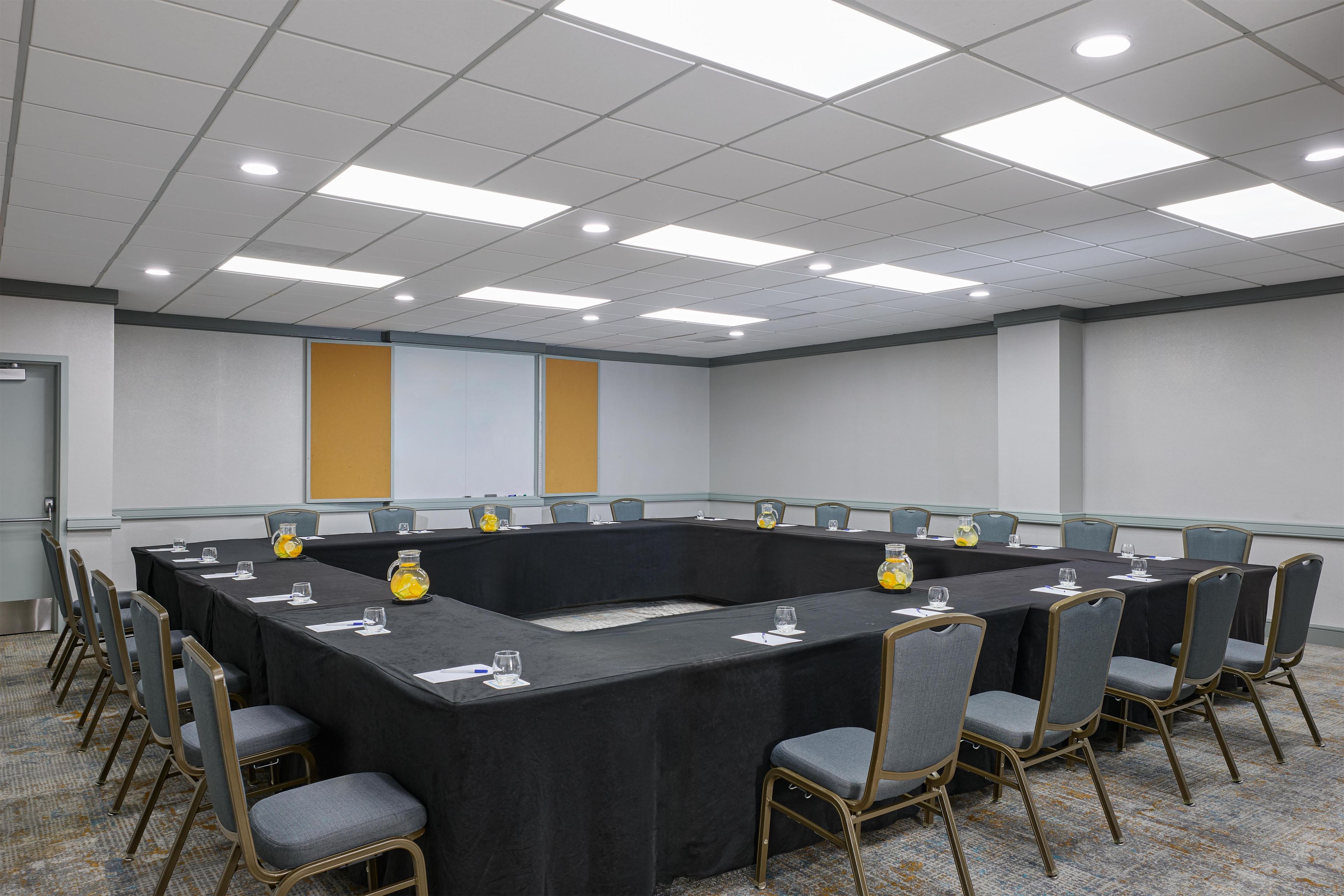 A conference room with a long table, chairs, and a projector screen.