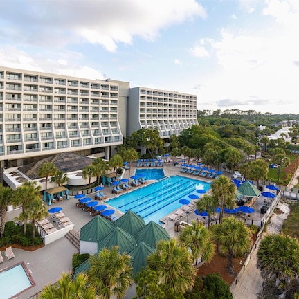 A hotel with a pool, beach, and palm trees.