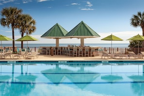 A poolside area with lounge chairs, umbrellas, and a bar area with bottles. - Hilton Beachfront Resort & Spa Hilton Head Island (Hilton Head Island)