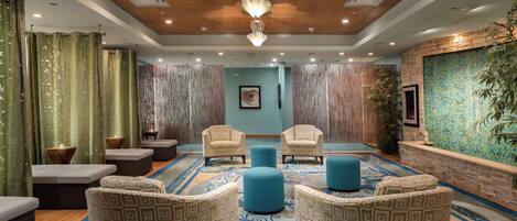 A lobby with patterned chairs, a blue carpet, and a wooden ceiling.